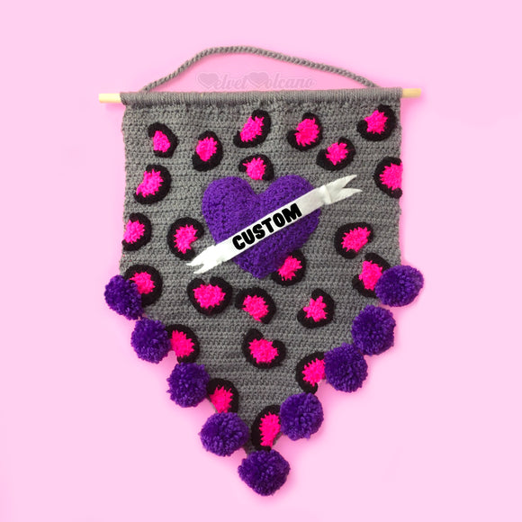 Grey crochet pennant wall hanging with pink and black leopard print and a purple love heart with a white felt banner over the top that says 