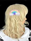 A crochet rainbow with clouds at both ends hair clip in a pale pastel rainbow colour way. Ultra Pastel Rainbow Cloud Kawaii Hair Accessory by VelvetVolcano