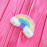 A crochet rainbow with clouds at both ends hair clip in a pale pastel rainbow colour way. Ultra Pastel Rainbow Cloud Kawaii Hair Accessory by VelvetVolcano