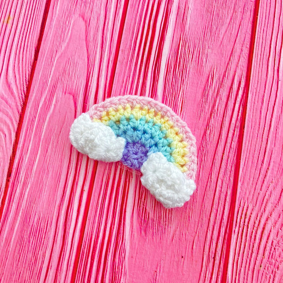 A crochet rainbow with clouds at both ends hair clip in a pale pastel rainbow colour way. Ultra Pastel Rainbow Cloud Kawaii Hair Accessory by VelvetVolcano