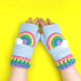 Light blue chunky crochet fingerless gloves with pastel rainbow striped cuffs and a pastel rainbow and cloud motif by VelvetVolcano
