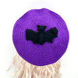 Purple crocheted beret with a black bat crocheted applique in the centre by VelvetVolcano