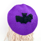 Purple crocheted beret with a black bat crocheted applique in the centre by VelvetVolcano