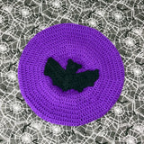 Purple crocheted beret with a black bat crocheted applique in the centre by VelvetVolcano