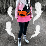 A photo of Tamsyn wearing a white and pink ombre biker jacket, a black sweater with white skeleton rib print, a pink corduroy mini skirt, black leggings, silver Dr Martens boots and an orange Creature Feature Bum Bag by VelvetVolcano. The background is a spooky looking wooded area. Tamsyn's head is out of frame but her brown hair can be seen in plaits.