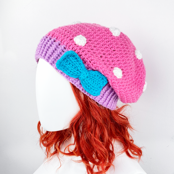 Bubblegum Pink crochet slouchy beanie with White polka dot pattern, Lilac contrast ribbed bottom section with a Turquoise bow positioned to the side on the ribbed section. Polka Dot Bow Slouchy Beanie (Custom Colour) by VelvetVolcano