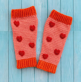 Peach crochet leg warmers with rose red heart pattern and pumpkin orange cuffs by VelvetVolcano. Background is pink brick.