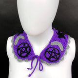 VelvetVolcano Witchy Collar, a violet Peter Pan style crochet detachable collar with black pentagrams, grey moons and black stars and a grey scallop trim around the bottom edge.