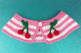 Bubblegum pink and white striped Peter Pan style detachable crochet collar with red and green cherry appliques on the lapels of the collar and a pink heart shaped button fastening. Cherry Stripe Collar by VelvetVolcano