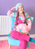 Tamsyn (a white woman in her early 30's with long plaited brown hair) is wearing a VelvetVolcano pastel rainbow outfit with cropped crochet sweater, circular shoulder bag and beret and hot pink Lucy & Yak dungarees