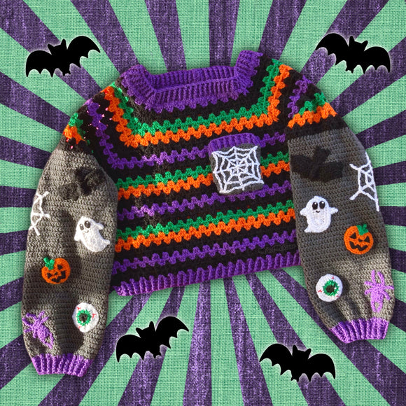 Black, purple, green and orange striped crochet jumper / sweater with spider web chest pocket and grey sleeves with bat, pumpkin, ghost, eyeball, spider and spider web applique designs. Cropped Spooky Season Sweater / Jumper by VelvetVolcano