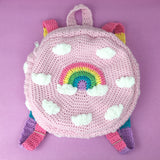 A fairy kei baby pink crochet circular backpack with a cloud and pastel rainbow rainbow design and pastel rainbow striped straps. Pastel Rainbow Cloud Backpack (Baby Pink) by VelvetVolcano