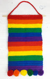 Rainbow striped crochet enamel pin & badge collection wall hanging with rainbow pom pom trim and wooden dowel hanger. Bright Rainbow Striped Pin Display Banner by VelvetVolcano